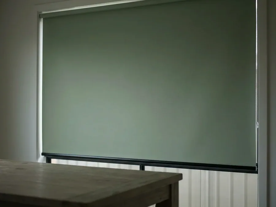 Blockout roller blind, one smooth sheet of fabric on a tube, lowered over a bedroom window